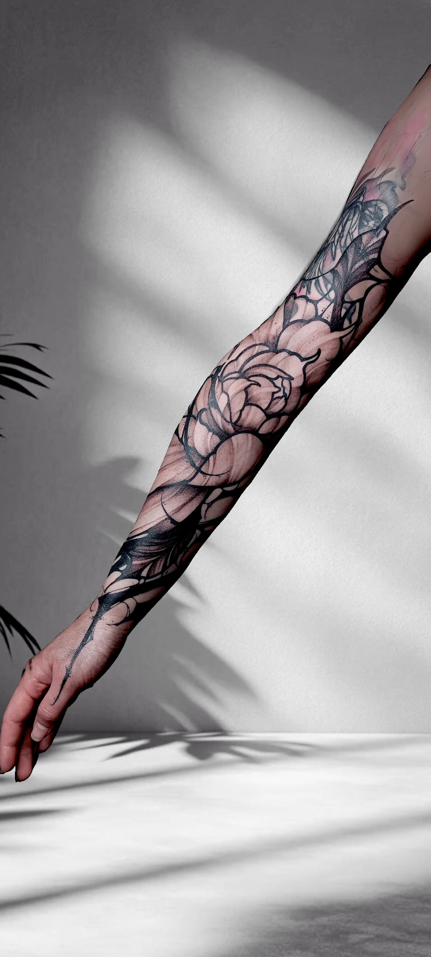 Ausgestreckter Arm und Hand mit einer dunklen, illustrativen Komposition aus Blüten und abstrakten Zweigen.