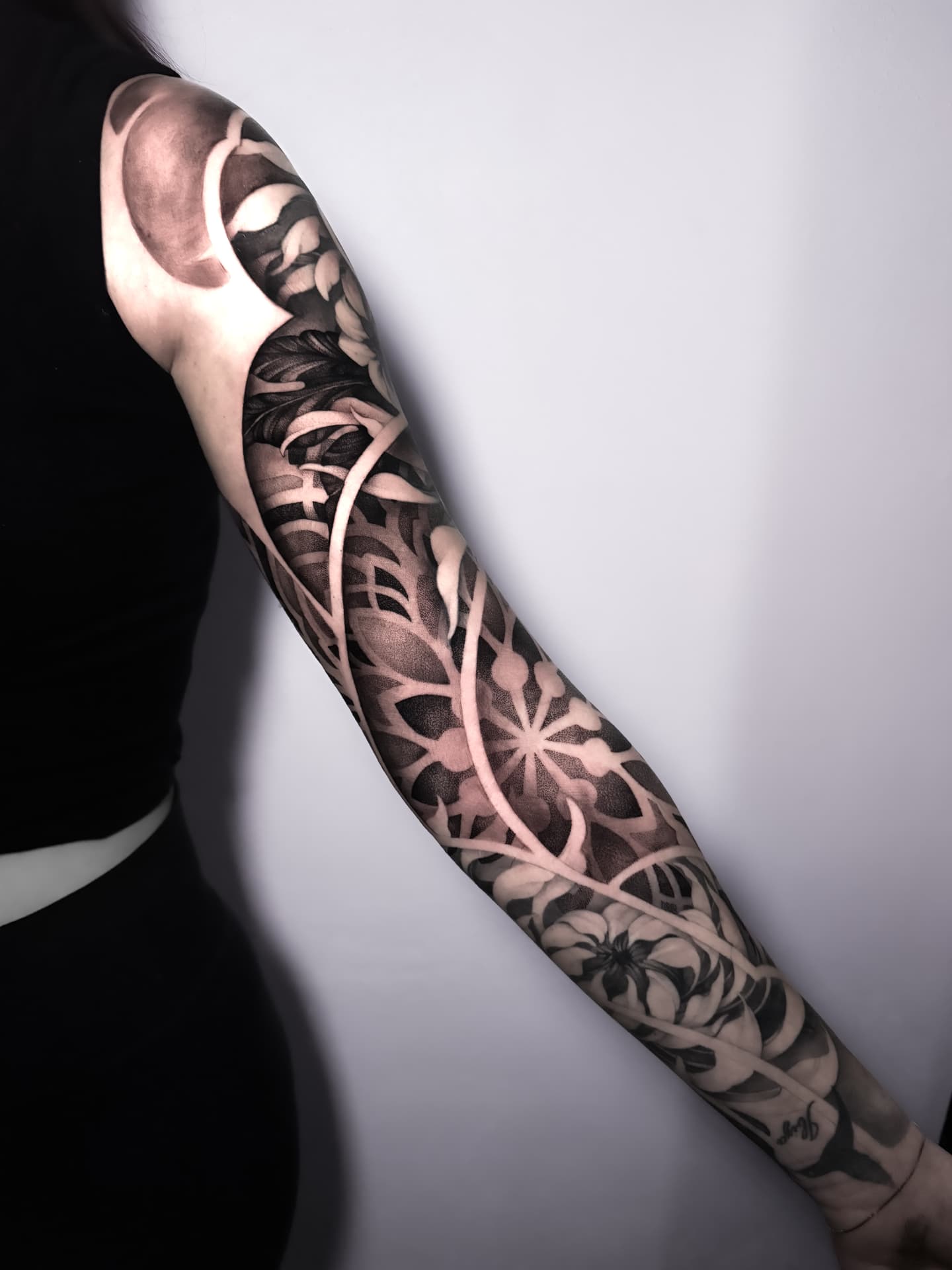 Nahaufnahme eines ganzen Ärmels: ornamentale Mandalas und botanische Blätter, getrennt durch freie Haut.